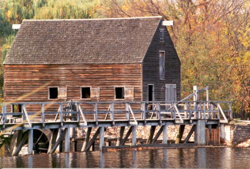 Philipsburg Manor building and bridge with yellow and orange fall leaves in the background.
