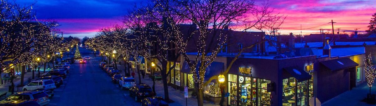 Aerial view of Downtown Glen Ellyn with holiday lights on trees at sunset