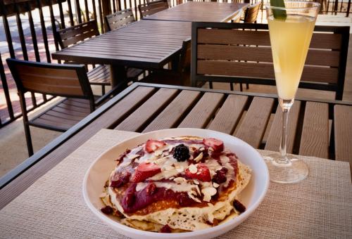 plate of pancakes with bananas and a champagne flute containing a mimosa drink