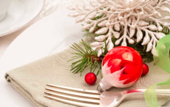 Fork and napkin on place setting with red ornament and artifical greenery