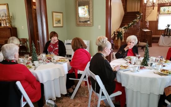 Group of women sitting in an historic home at tables, having tea