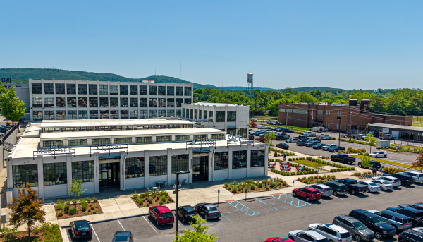 Aerial image of Lincoln Mill business district with mountains and the Lincoln Mill water tower in the background on a bright, sunny day.