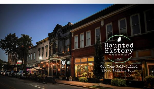 Haunted History Jeffersonville showing historic Main Street buildings at night with lit storefronts and glowing signage city.