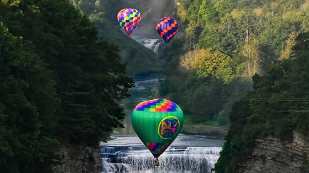 Hot air balloons fly over a waterfall at Letchworth State Park