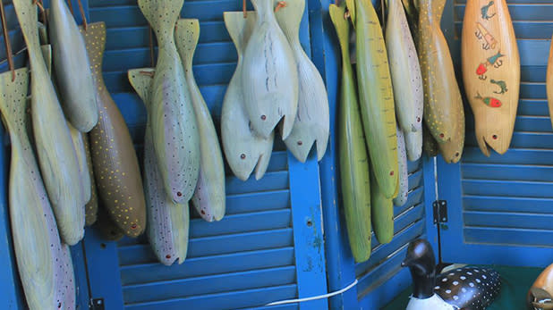 Handcrafted wooden fish in varying colors of blue and green are displayed at the Adirondack Artisan Festival