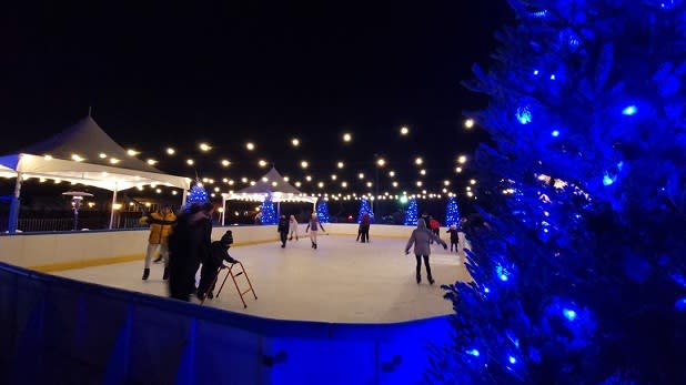 Families skate on the ice rink at Rocking Horse Ranch under a canopy of string lights