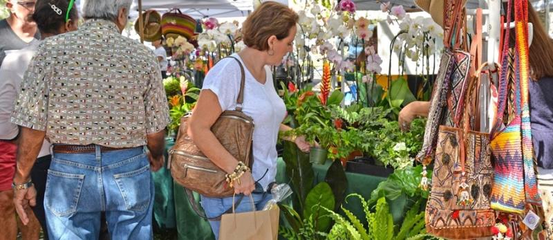 A woman looking at potted plants and orchids at an outdoor market