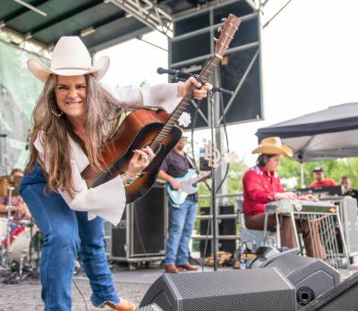 Female guitarist on stage, smiling at the camera