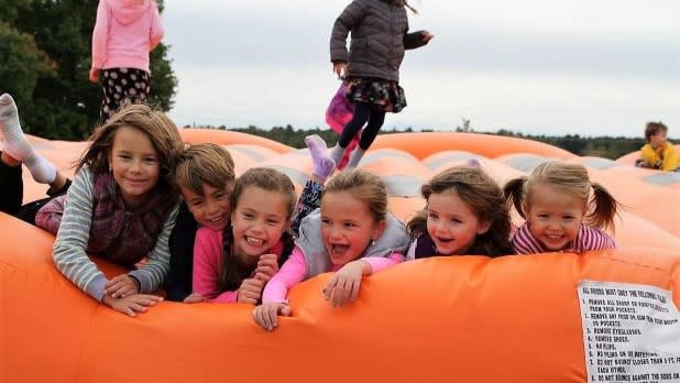Six children lay on an orange jumping pad at Ellms Family Farm