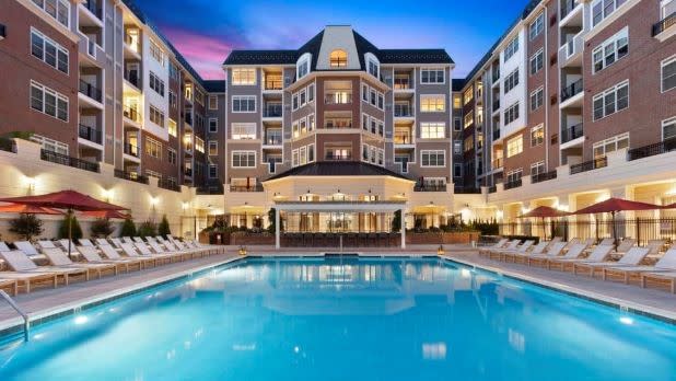 Various hotel room balconies frame a outdoor pool surrounded by lounge chairs