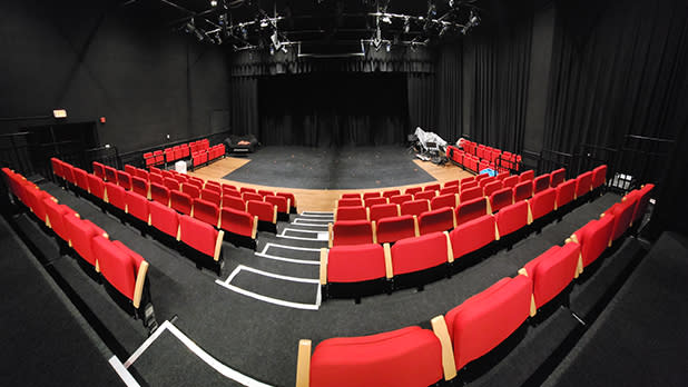 Rows of red upholstered seats inside the Ujima Theater