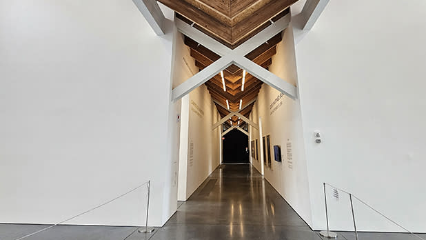 View of a long hallway with white walls and natural wood beam ceiling at the Parrish Art Museum