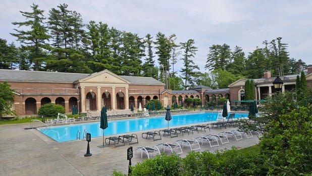a bright blue pool surrounded by lounge chairs and arched promenades