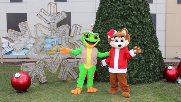 Two costumed characters stand near a holiday display at Jingle Falls USA