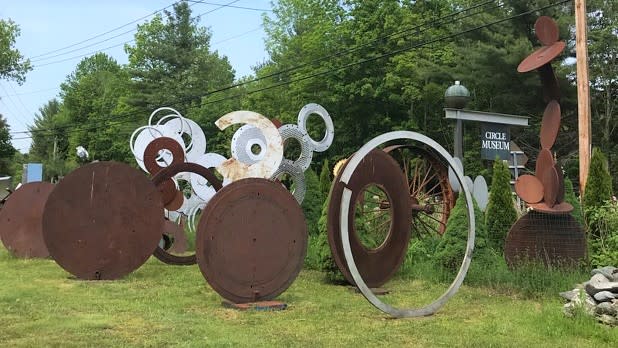 Rusted scrap metal sculptures in the shapes of circles line the outside of the Circle Museum
