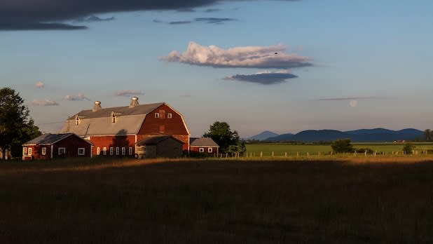 View of farmland and a red barn in the distance in Plattsburgh along the Lakes to Locks Passage