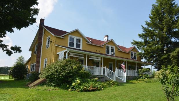 Exterior of yellow house with white porch at the Inn at the Ridge in Wallkill, New York