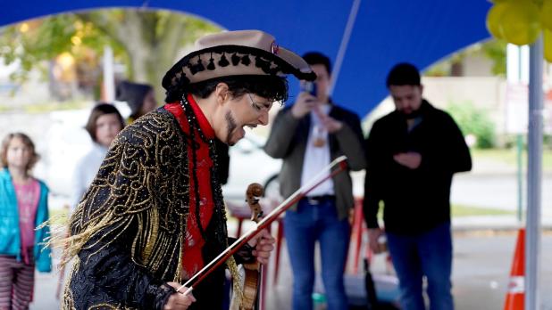 A man in traditional clothing sings while holding a violin