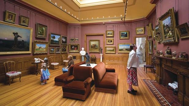 Artwork hangs on the maroon walls of the Arnot Art Museum