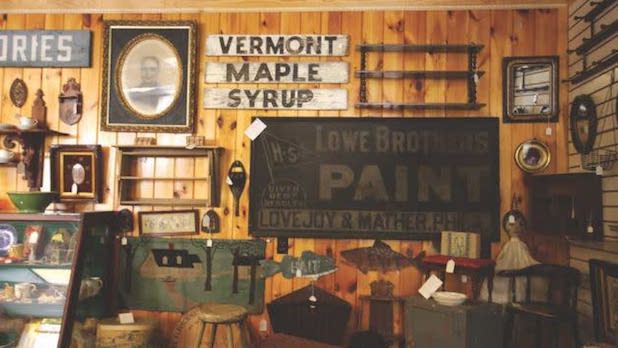 a variety of eclectic antiques like signs, photos, and shelves on a wall along the interior of the Ballston Spa Antique Center