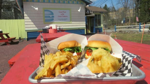 Two burgers, fries, and fried pickles in front of Mama's Boys Burgers, Tannersville, New York