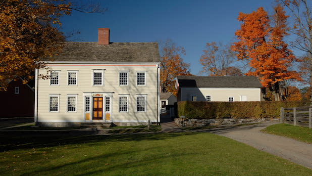 exterior of a white country house surrounded by trees with fall colors