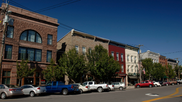 Brown, white, grey, and red buildings and cars line the streets of Clayton