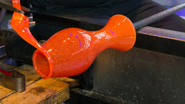 An orange glass being spun at Corning Museum of Glass