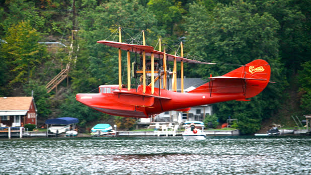 A red boat plane from Glenn Curtiss Museum flying over the lake