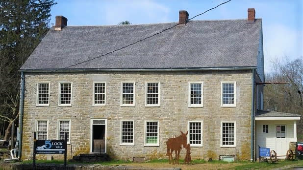 A statue depicting a girl leading a mule stands outside the stonework building that houses the D&H Canal Museum