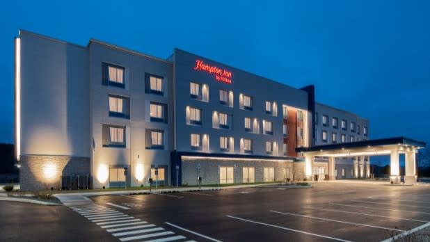 Yellow/white lights illuminate the exterior of the Hampton Inn Cooperstown at night