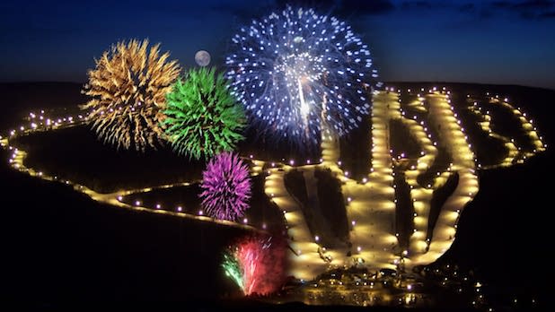 vibrant fireworks erupt over an illuminated ski mountain for New Year's Eve