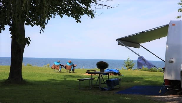 A couple sits in a pair of camp chairs looking out at Lake Ontario at Four Mile Creek campground