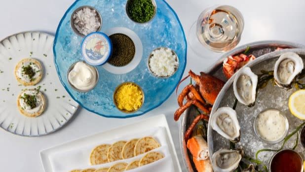 Plates of oysters, lobster,  and other food on a white table