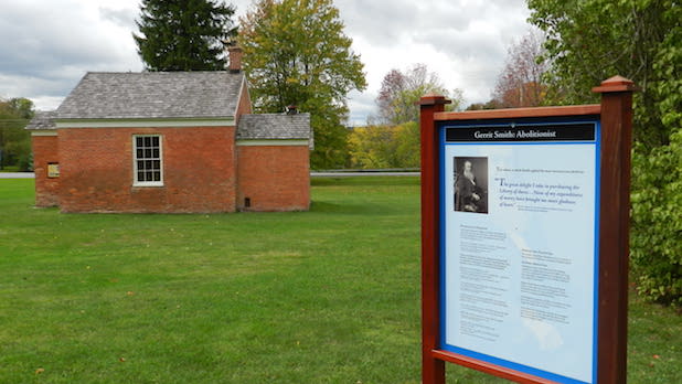 an informational sign about abolitionist, Gerrit Smith with a historic brick building in the background