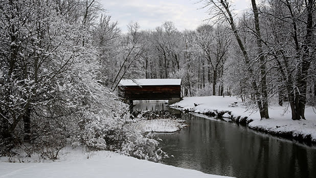 A snowy scene featuring Hyde Hall Covered Bridge in Glimmerglass State Park