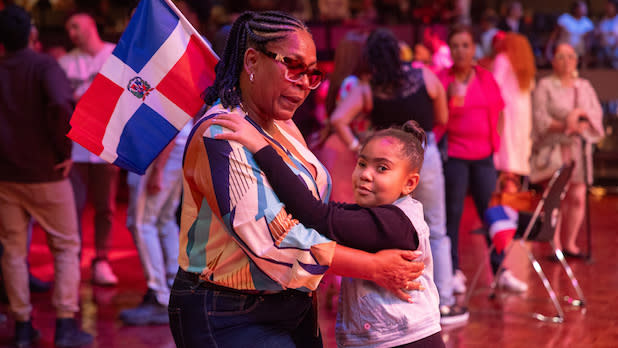 A woman and a child dance while holding the flag of the Dominican Republic