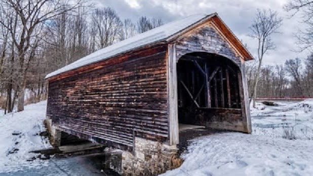 Wooden exterior of the Hyde Hall Covered Bridge in the snow