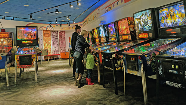 Family playing pinball at Strong National Museum of Play