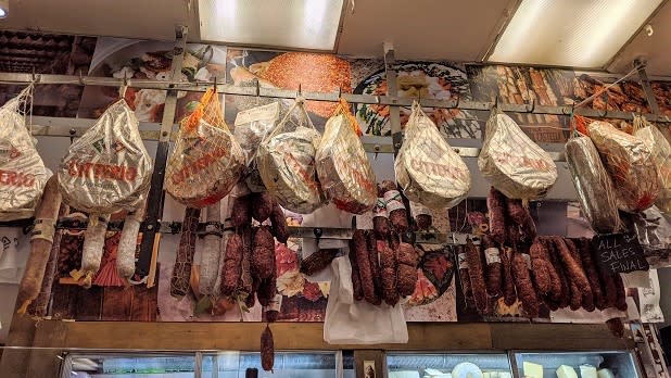 Cured meets, salamis, and other offerings hang above the counter at Arthur Avenue Retail Market