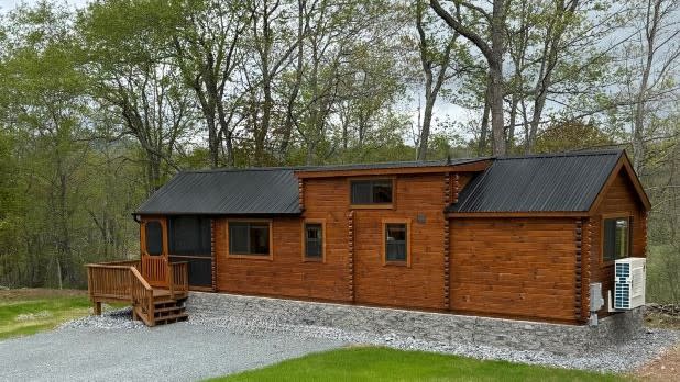 A small cabin in the Catskills with dark brown wood and a black roof