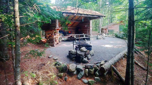 A wooden lean to stands behind a fire pit at one of the camp sites at International Paper-John Dillon Park