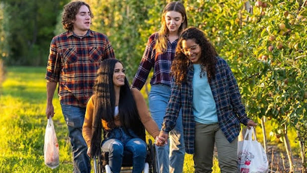 Two couples stroll through an apple orchard holding hands