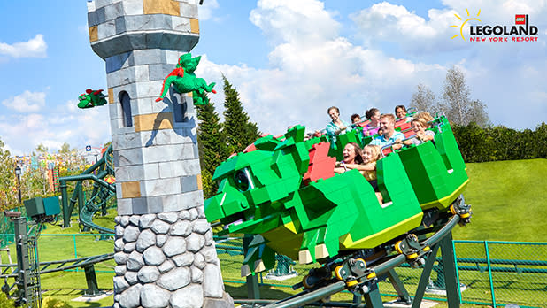 Guests ride a Lego dragon coaster by a tower