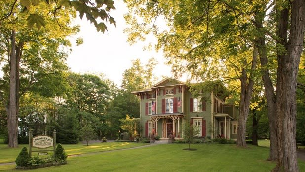 Lush green grass and trees surround the quaint Landmark Inn in Cooperstown