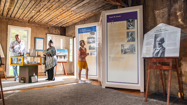 Three people looking at museum exhibits inside the John W. Jones Museum