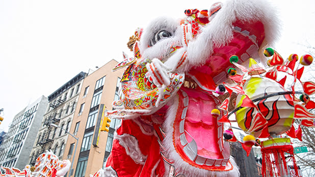 Colorful red, pink, white and yellow Chinese dragon puppet with NYC street in background