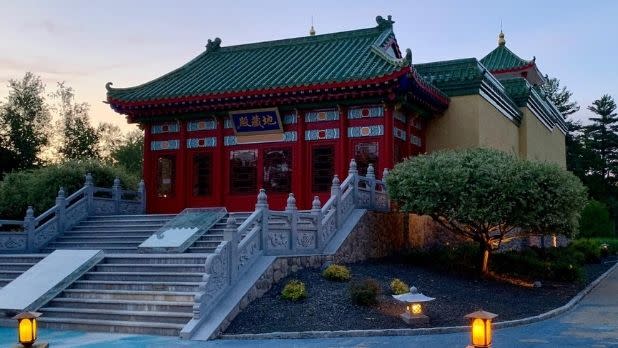 The red Mahayana Buddhist Temple with traditional stairs and green roof with lanterns along the pathway