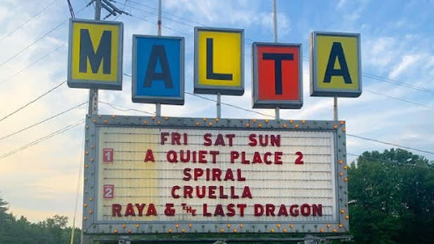 Exterior of a sign spelling out "Malta" above current movie showings