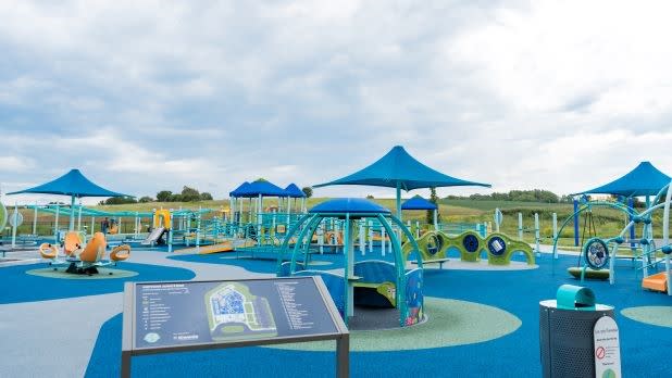 Blue, green, and yellow apparatuses at Motion Junction inclusive playground in the Finger Lakes.